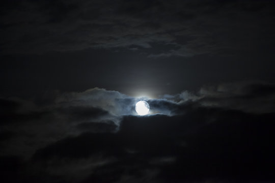 Moon shining in cloudy night sky.