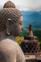 Meditating sitting Buddha sculputre sideview in stone at Borobudur Indonesia