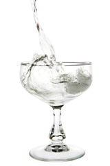 Liquid champagne poured into empty glass on white background. Clipping path incl.