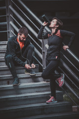 Couple resting on the stairs after running
