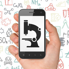 Science concept: Hand Holding Smartphone with Microscope on display