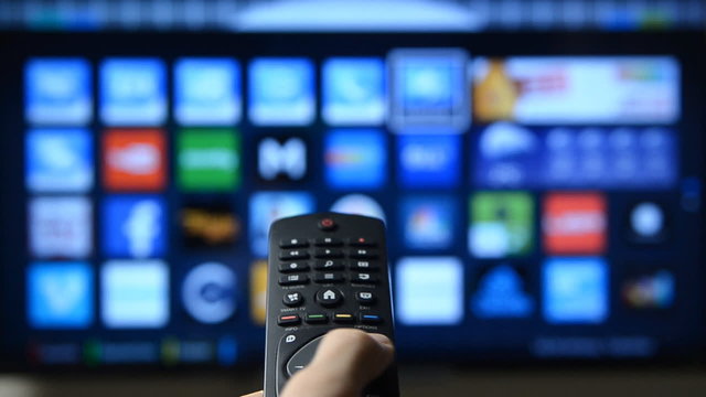 Smart tv and hand pressing remote control.