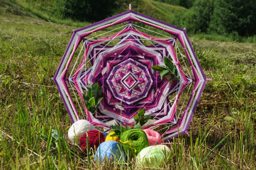 Knitted woven mandala with yarn on the grass