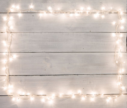 Christmas lights on white painted wooden background with copy sp