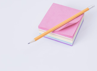 colored paper for notes rainbow on a white table. White background. Orange pencil.