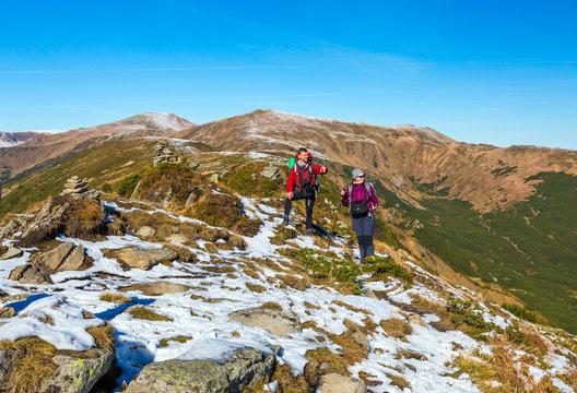 Two Hikers staying on winter Mountain terrain pointing