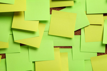Image of blank green and yellow sticky notes on cork bulletin bo