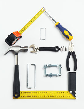 Image of tools in shape of house over white background. Home imp