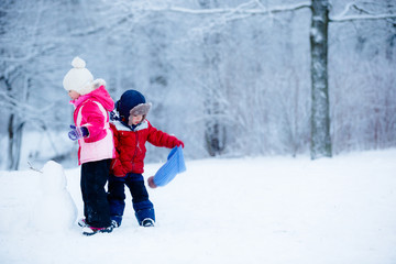 Fototapeta na wymiar Little boy and girl molding a snowman