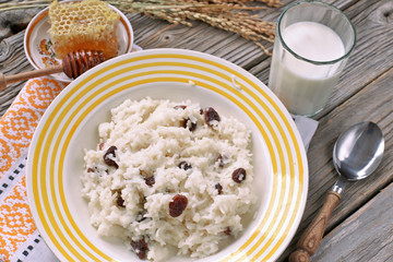 Rice cereal with raisins , honey, milk on wooden table 