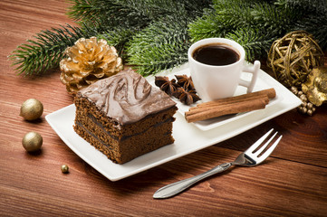 A piece of  christmas gingerbread cake on the white plate on the festive table.