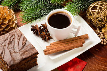 A piece of  christmas gingerbread cake on the white plate on the festive table.