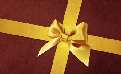 Shiny golden satin ribbon bow on red background