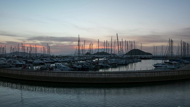 A harbour view at sunset. Yacht marina with night illumination. 4k, Time lapse