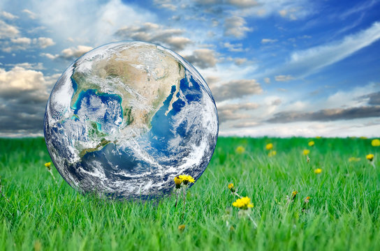 Earth among the green grass against the blue sky. Elements of this image furnished by NASA