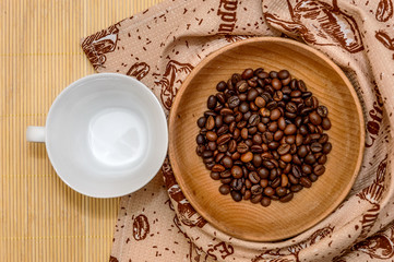 White cup and a wooden bowl with coffee beans