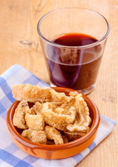glass of wine and pork rinds on wooden board