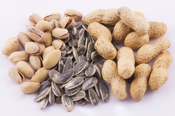 Pistachios, sunflower seeds and peanuts on white background