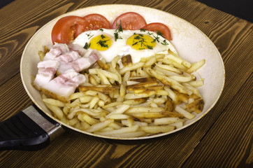 Breakfast for two. Frying pan with two fried eggs and fried pota