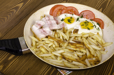 Breakfast for two. Frying pan with two fried eggs and fried pota