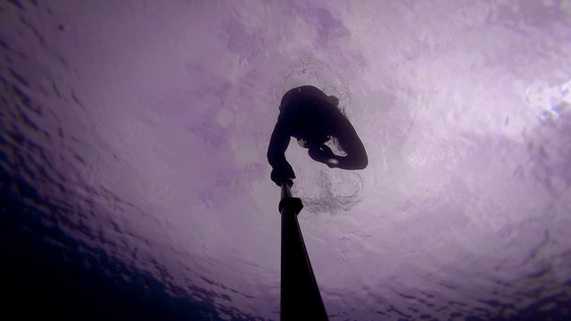 Freediver Going Underwater for a While and Deep and also passing under Wood platform.