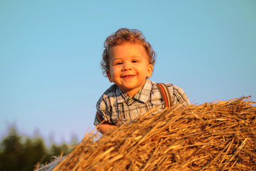 Naklejka na ściany i meble Cute boy playing with a hay 