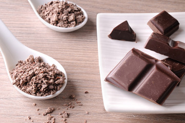 Portions and chocolate chips on white container on wood table