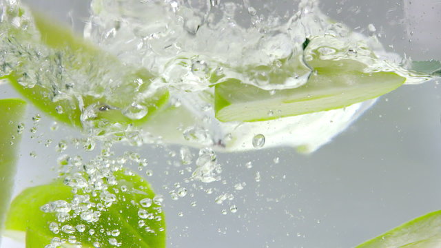 Super Slow Motion Fresh Green Apple Slices Falling into Clear Water