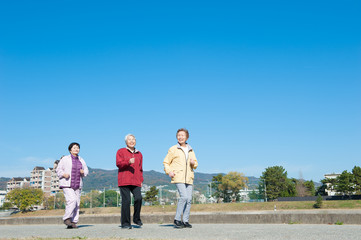 青空を背景に歩いている3人のアジア人高齢者