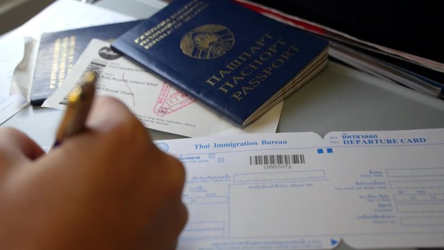 Hand Filling Arrival and Departure Card with Passport