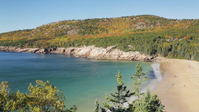 Sand Beach and the Atlantic Ocean, backed by Gorham Mountain lined with trees colored with near peak Autumn foliage, Acadia National Park, Maine.