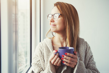 pretty girl drinking coffee or tea in morning sunlight near wind