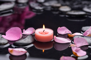 Pink rose petals with candle and therapy stones 