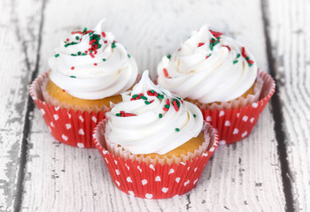 Holiday cupcakes with vanilla frosting on vintage wooden background. Shallow depth of field.