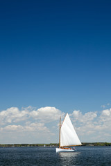 Fototapeta premium Single Sailboat as viewed on a beautiful Spring day from the Chesapeake Bay Maritime Museum in Saint Michael's, Maryland.