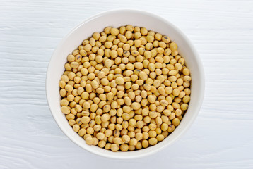 Soybeans in ceramic bowl on wood background.
