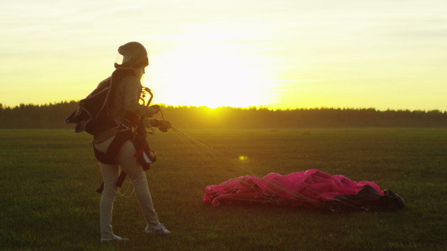 Girl Skydiver is Folding his Parachute after Successful Landing. Shot on RED Cinema Camera.