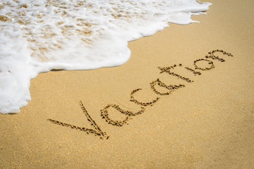 Word vacation on the beach sand - vacation and travel concept