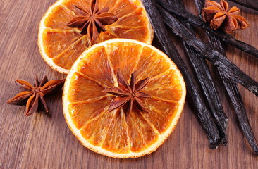 Fragrant vanilla, star anise and dried orange on wooden surface plank