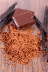 Powdery cocoa, dark chocolate, fragrant vanilla sticks on wooden surface