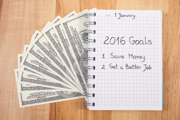 Naklejka premium New years resolutions written in notebook and currencies dollar