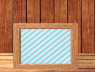 Photo frame on wooden table over wooden background