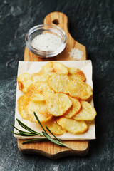 Homemade potato chips with sea salt and herb on wooden cutting board