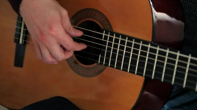 Man's hands playing guitar .