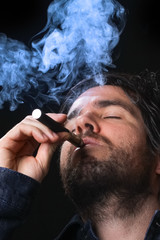 Young man smoking electronic cigarette on black background