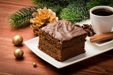 A piece of  christmas gingerbread cake on the white plate on the festive table.