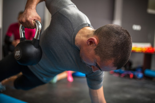 Young man lifting dumbbell and kettlebell at the fitness center