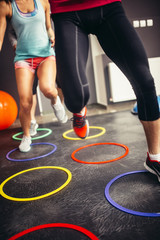 People at the gym jumping over fitness rings.Grain effect added for artistic impression.