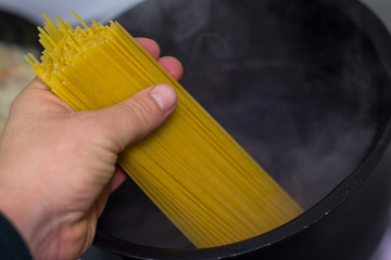Hand puts spaghetti to boil
