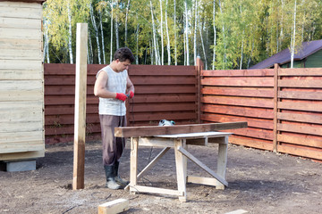 man turns on power circular saw for cutting beams